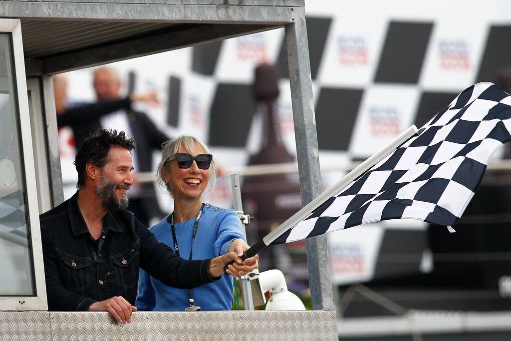     Keanu Reeves and Alexandra Grant wave the checkered flag 