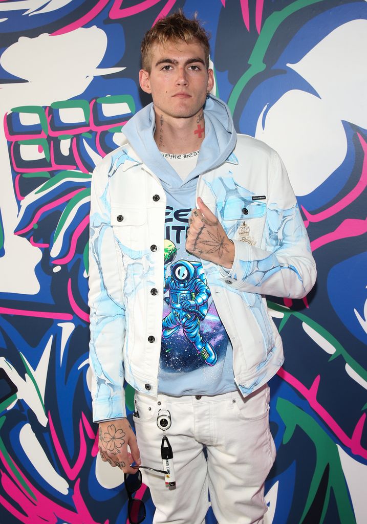 Presley Gerber wearing a blue hoodie and white denim jacket 